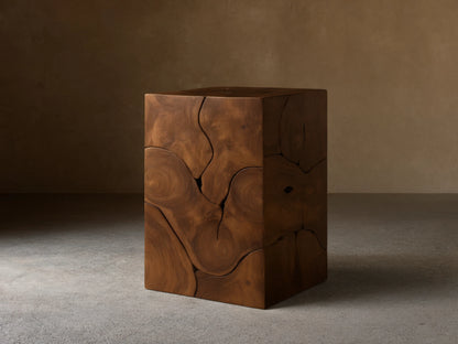 Kalmar Pedestal in natural teak wood featuring organic cracks, knots, and swirling patterns on a smooth, cube-shaped design.