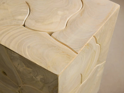 Alt text: Kalmar Pedestal made of natural teak wood featuring organic circular patterns and visible cracks on its rectangular surface, standing on a wooden floor against a neutral wall.