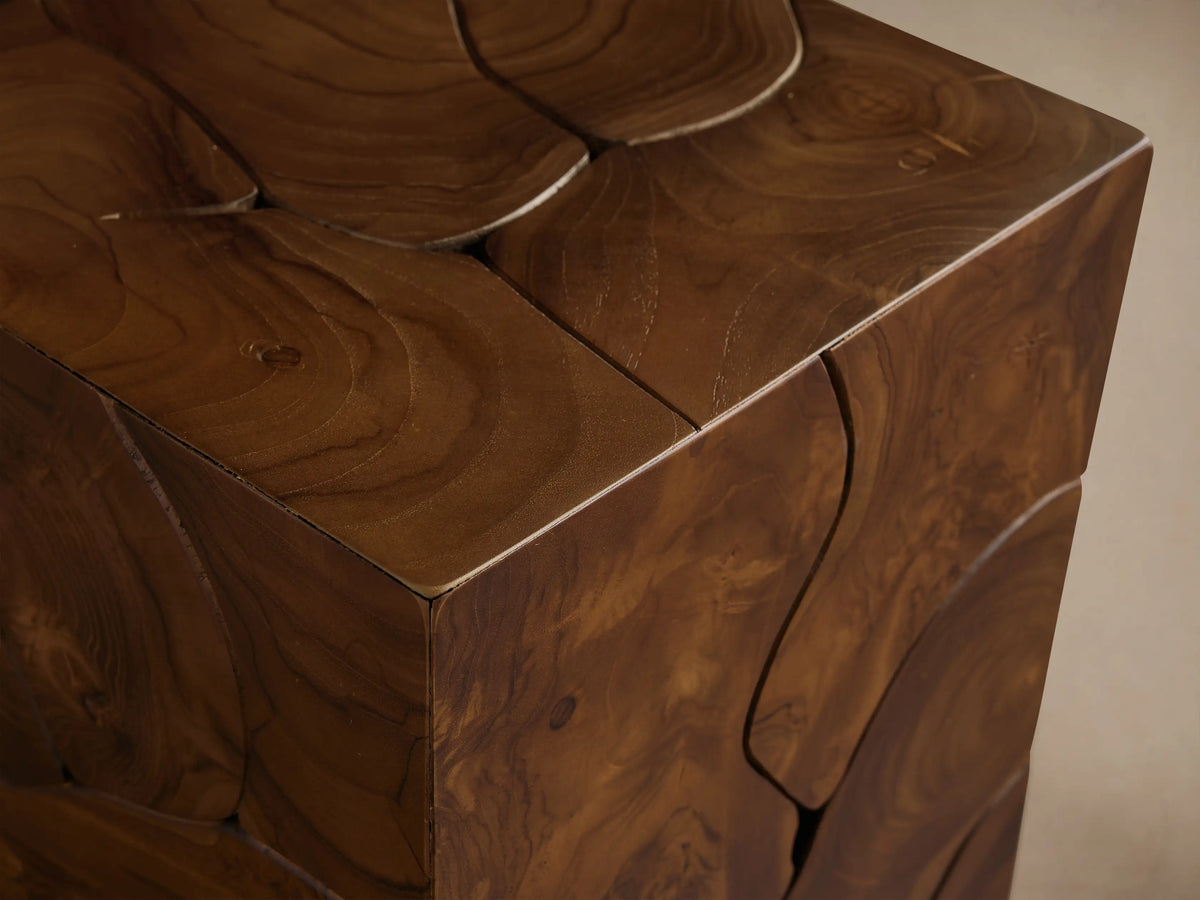 Kalmar Pedestal made of natural teak wood with visible organic patterns, cracks, and knots, standing on a wooden floor.