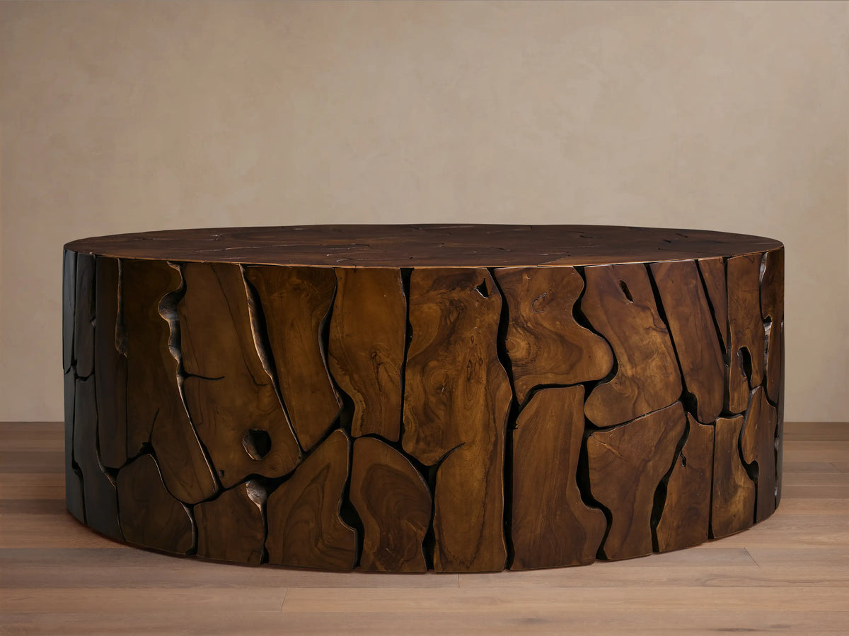 Kalmar Round Coffee Table made of teak wood with dark, organic patterns, visible cracks, and knots on surface, placed on wooden floor.