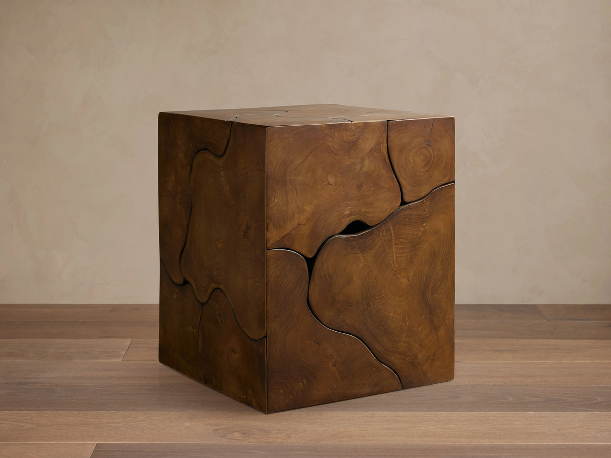 Kalmar End Table made of natural teak wood, displaying organic shapes, cracks, and unique patterns, placed on a wooden floor.