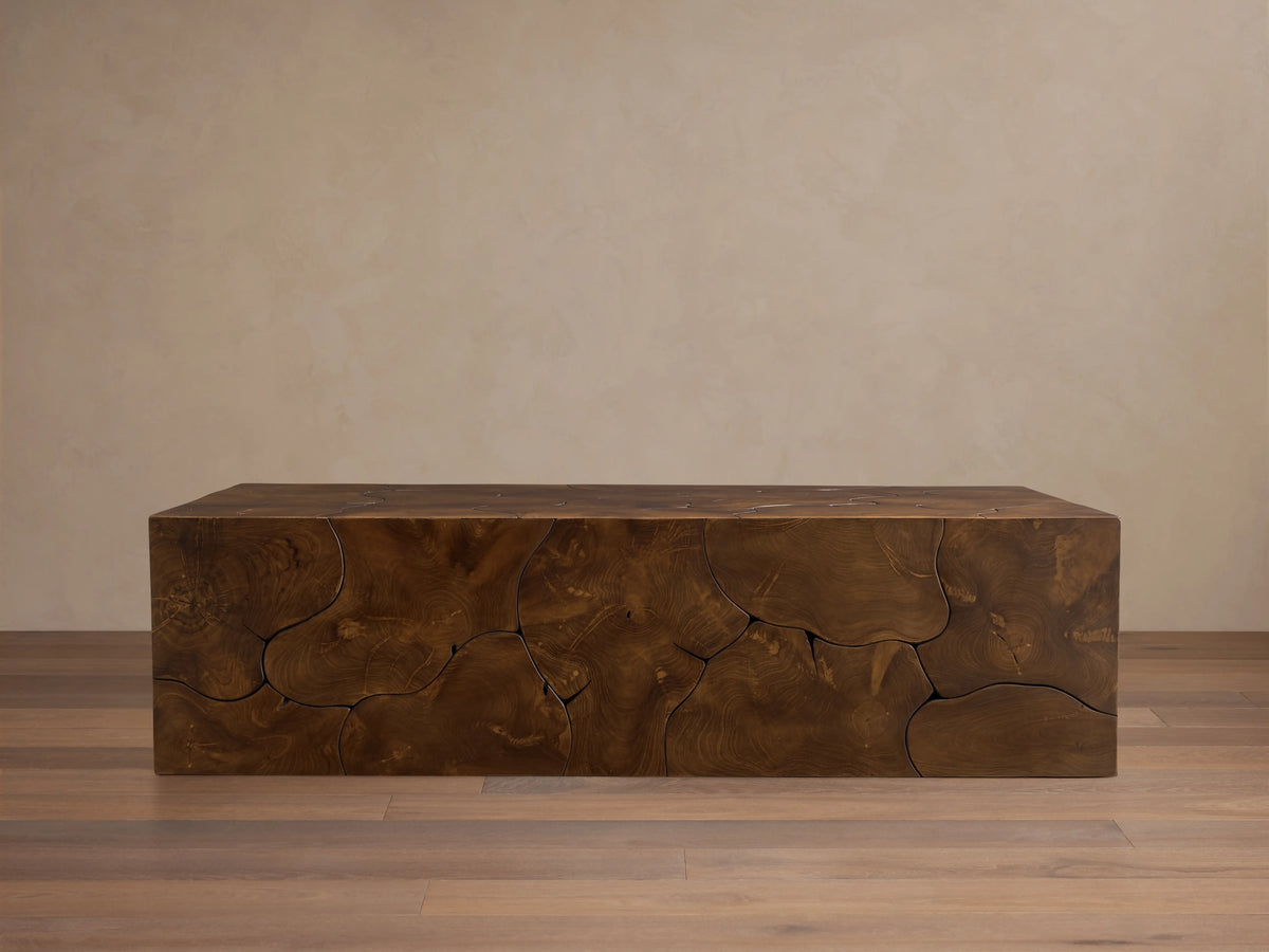 Kalmar Coffee Table made of natural teak wood with visible organic shapes, cracks, and a rich brown patina, on wooden floor.