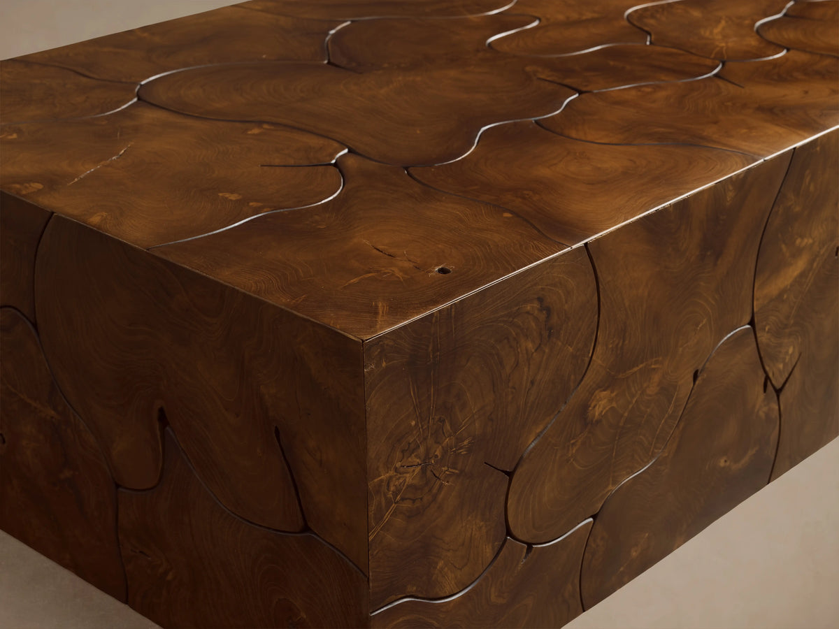 Kalmar Coffee Table made of natural teak wood with visible organic shapes, cracks, and a rich brown patina, on wooden floor.