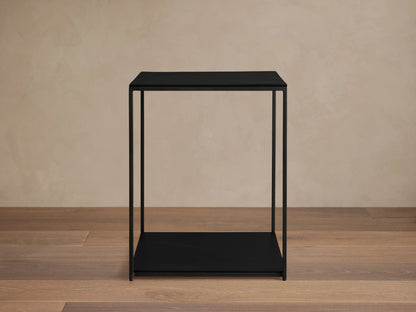 Kavali Square End Table with a black powder-coated finish, solid iron frame, and minimalist design on a wooden floor.