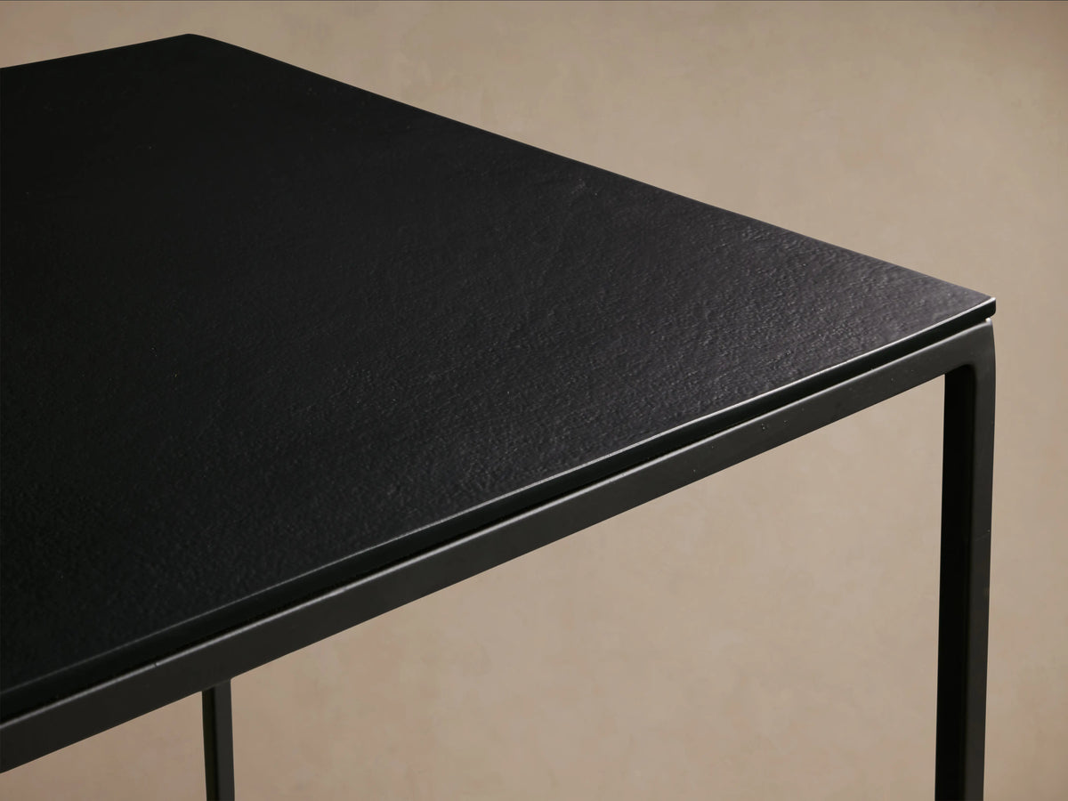 Kavali Square End Table with black, powder-coated iron frame; close-up of smooth, square aluminum top with subtle texture.