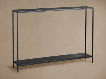 Kavali Slim Console Table, black powder-coated iron frame, rectangular with narrow tabletop and base shelf, on wooden floor.