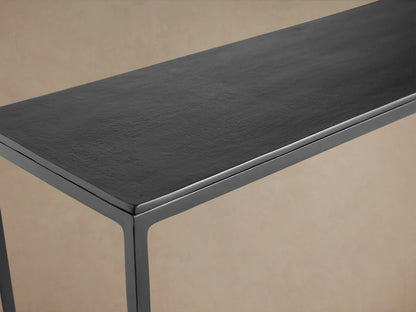 Kavali Slim Console Table in black iron, featuring a minimalist rectangular frame with a lower shelf, against a beige background.