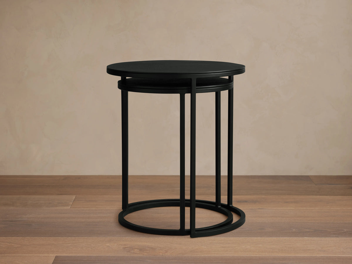 Kavali Nesting End Table with solid iron frame in black powder-coated finish. Round top with minimalist design, nested on wooden floor.