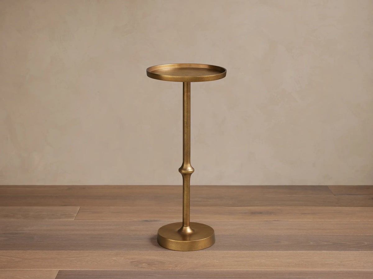 Two bronze-toned Kenneth Martini Tables with slender round tops, one taller, in a living room setting.