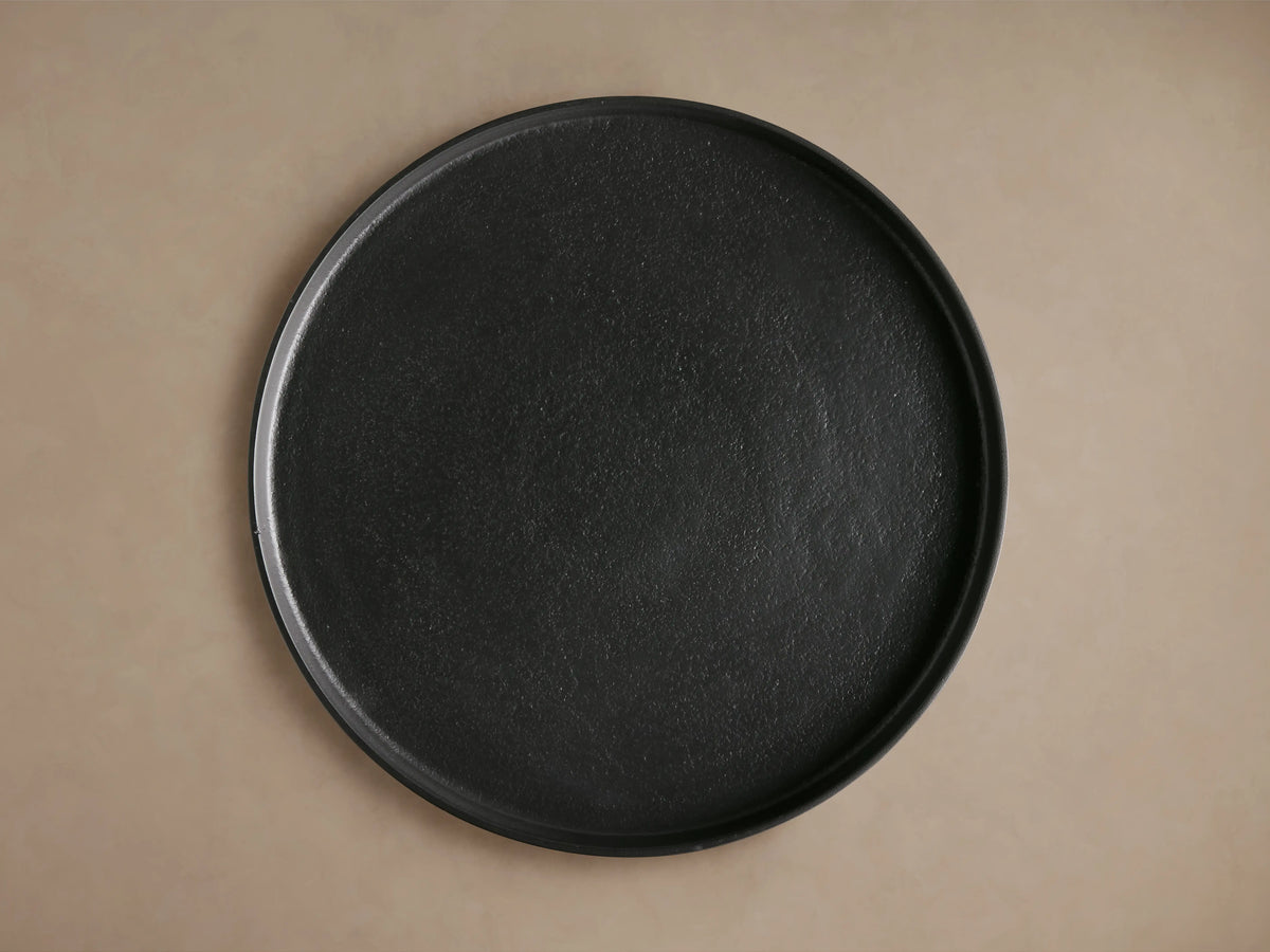 Kenneth Martini Table, top view showing round, dark cast aluminum surface with unique textured finish on a neutral background.