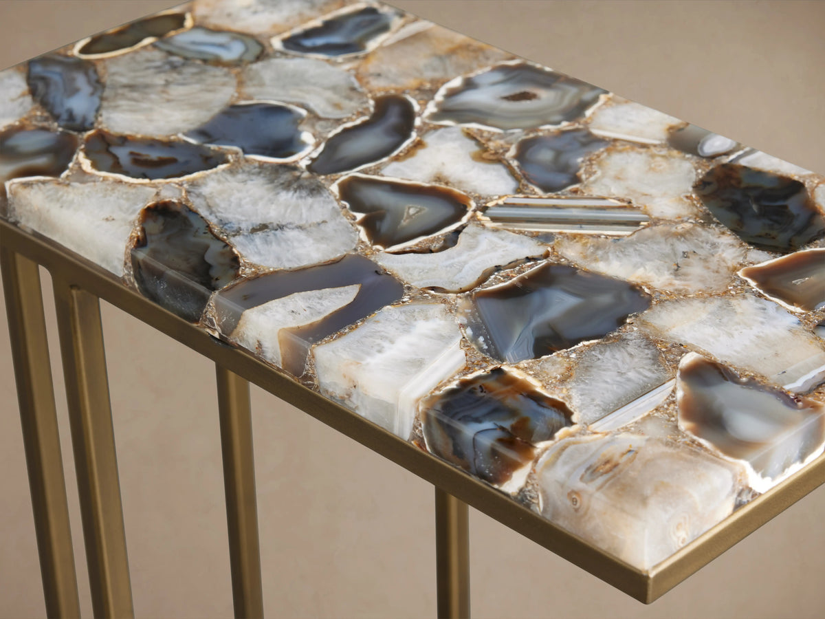 Ludlow C Table with a stone tabletop featuring polished stones in blue, gray, and brown hues, atop a gold-colored iron base.