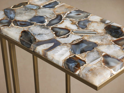 Ludlow C Table with a stone tabletop featuring polished stones in blue, gray, and brown hues, atop a gold-colored iron base.