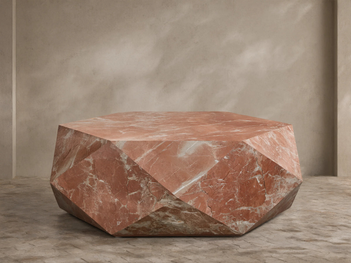 Front view of a faceted, hexagonal coffee table made of pink marble with white veins.