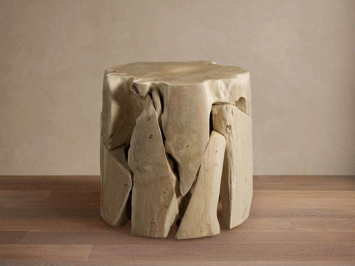 Maggie Stool made of natural wood, featuring a unique, irregular texture with visible grain and rough-hewn edges on a wooden floor.