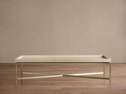 Malone Coffee Table with light beige shagreen leather tabletop and gold metal X-base, centered on a wooden floor.