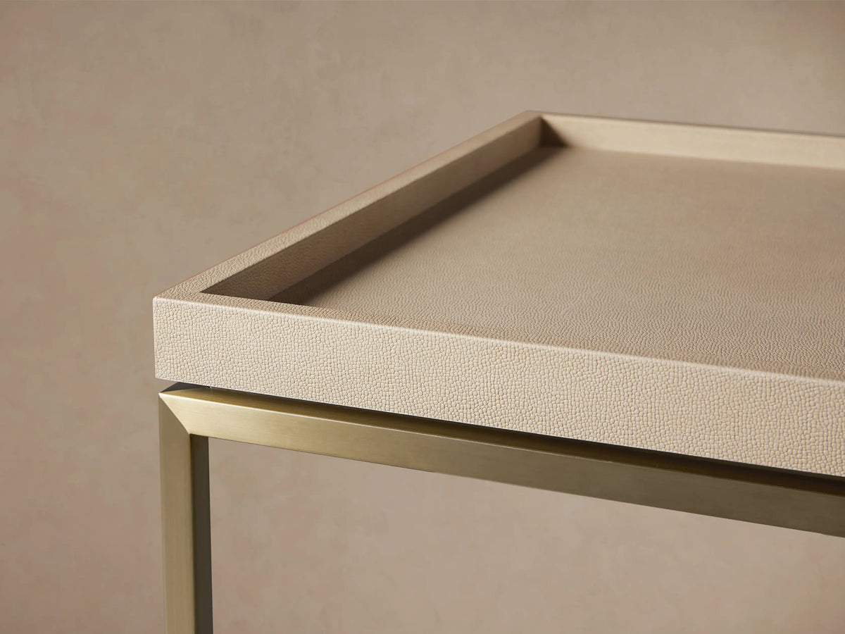 Malone Coffee Table with light beige shagreen leather tabletop and gold metal X-base, centered on a wooden floor.