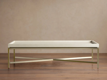Malone Coffee Table with light beige shagreen leather top, supported by a champagne gold steel base, angled on a beige background.
