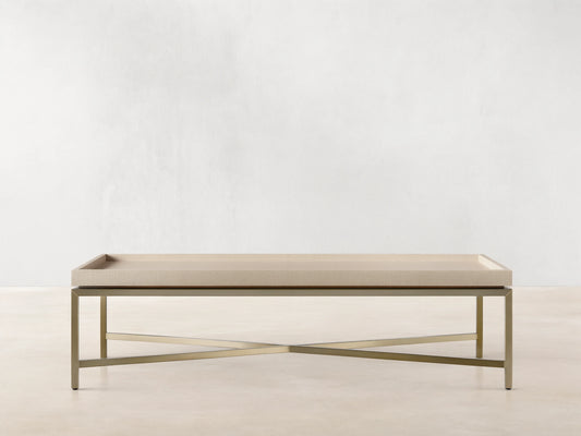 Malone Coffee Table with light beige shagreen leather tabletop and gold metal X-base, centered on a wooden floor.