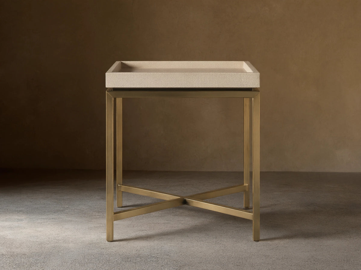 Malone End Table with a beige shagreen-patterned tray top and a metallic gold X-stretcher base, viewed straight on in a room.