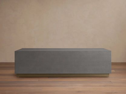 Malone Plinth Coffee Table with a rectangular shape, gray shagreen-patterned surface, and a brass-finished steel base, on wooden flooring.