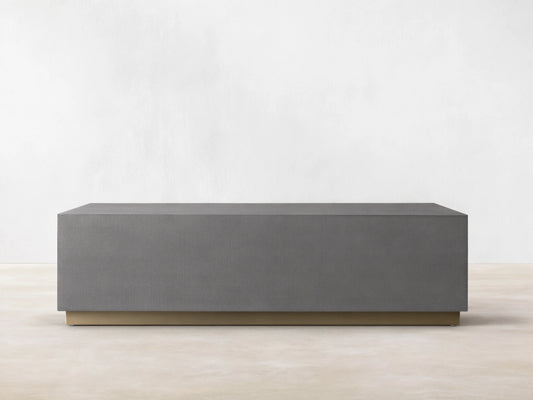 Malone Plinth Coffee Table with a rectangular shape, gray shagreen-patterned surface, and a brass-finished steel base, on wooden flooring.