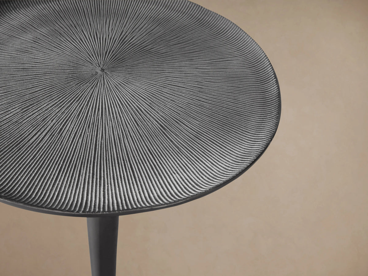 Manhattan Martini Table with a slim, elegant cast aluminum base and a round, textured tabletop, finished in dark zinc.