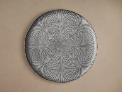 Manhattan Martini Table with a textured, black tabletop featuring radiating grooves, supported by a sleek, dark base on a neutral background.