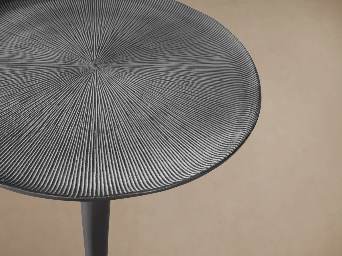 Manhattan Martini Table: Dark metallic, circular textured top, sleek hourglass pedestal, and round base, on wood floor.