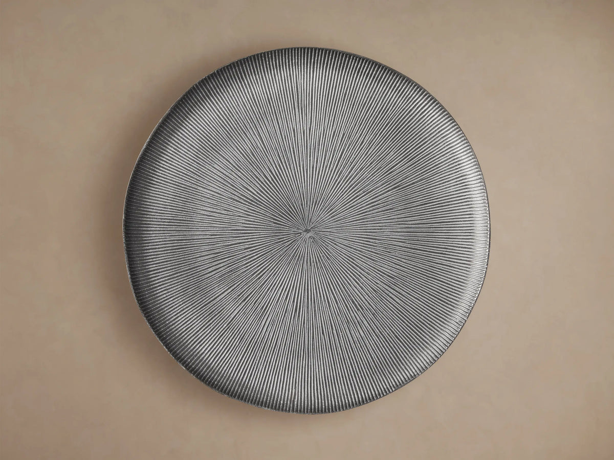 Manhattan Martini Table, close-up of dark grey round top with white-washed radial texture, smooth base, against a beige wall.