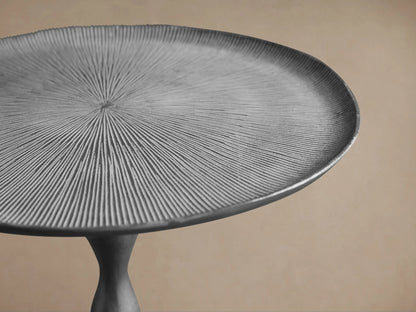 Manhattan Martini Table. Dark grey metal with textured white-washed round top, a slender curved stem, and round base.
