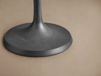 Close-up of the Manhattan Martini Table's round, dark grey top with prominent radiating textured lines, and smooth base.