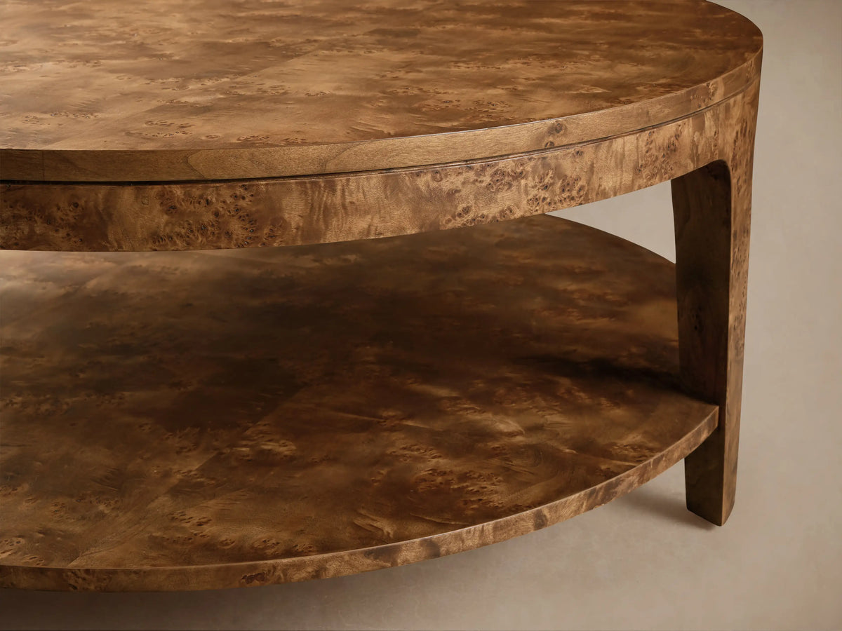 Round mappa burl veneer Mogadore Round Coffee Table with lower shelf, styled with books and flowers in a bright living room.