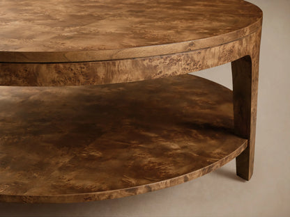 Round mappa burl veneer Mogadore Round Coffee Table with lower shelf, styled with books and flowers in a bright living room.