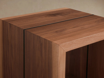 Mihaela End Table in a cubic design with a hollow center, crafted from wood, on a wooden floor with a neutral wall.