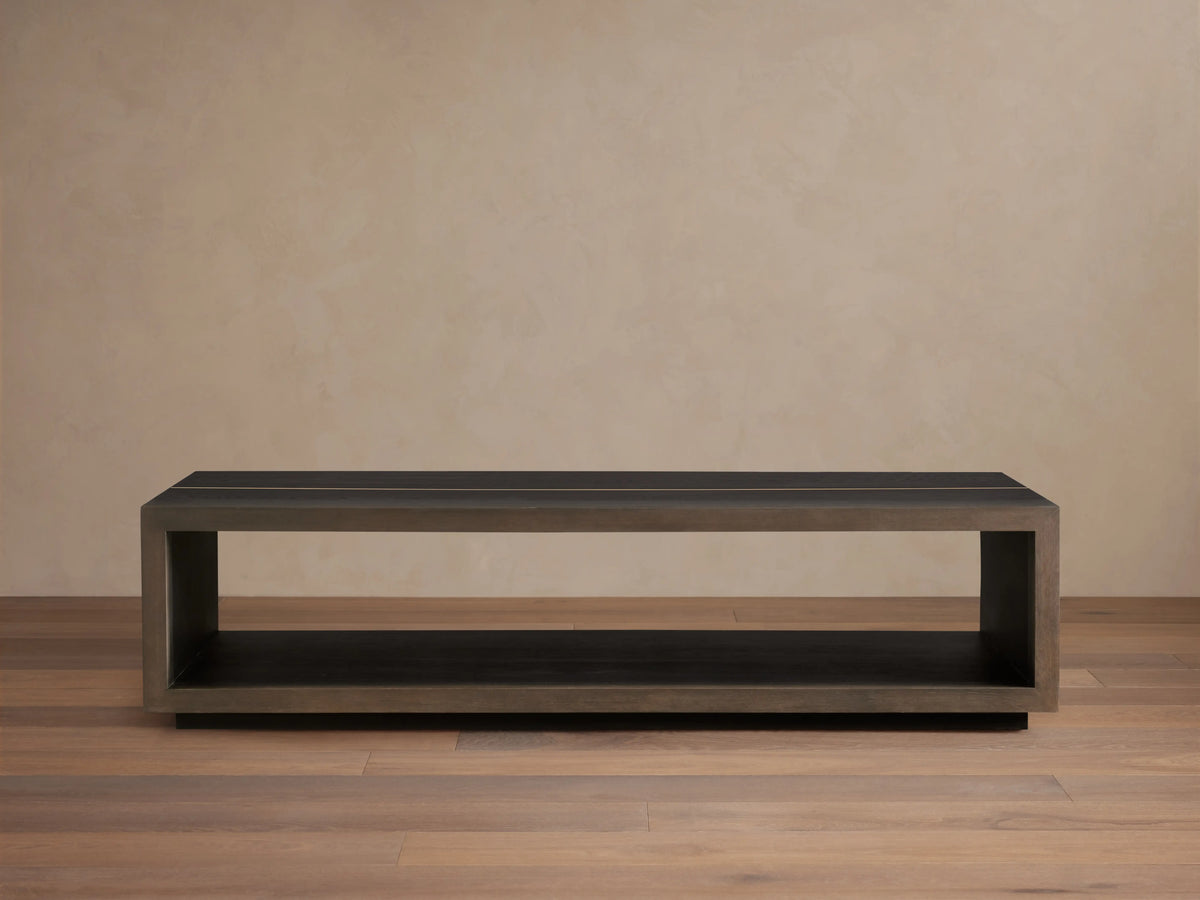 Mihaela Coffee Table in solid wood with a rectangular open-frame design, dark finish, and metallic-like accents on a wooden floor.