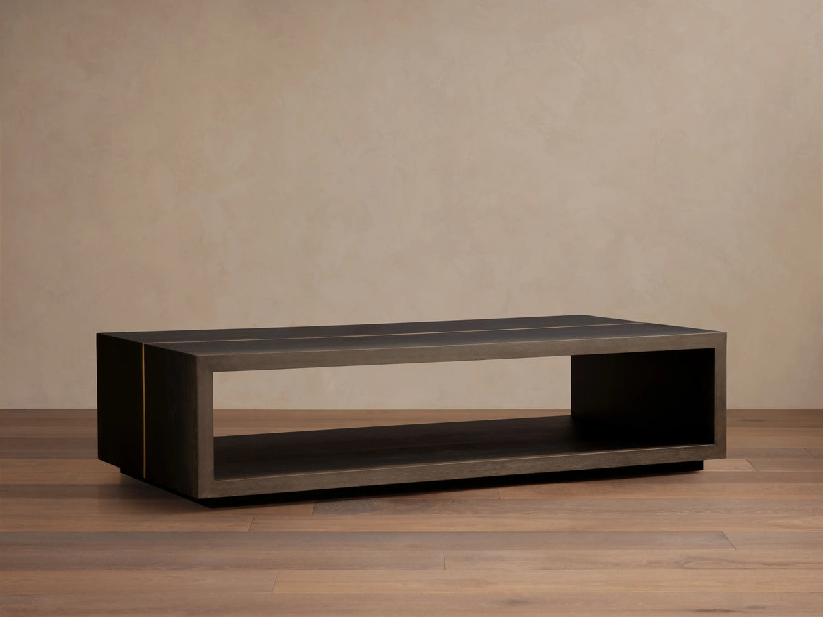 Mihaela Coffee Table in dark finish showing rectangular design, open shelf, on light wood floor; sleek, minimalist style.