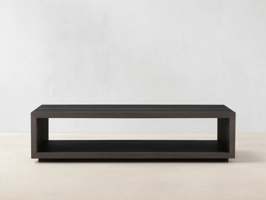 Mihaela Coffee Table in solid wood with a rectangular open-frame design, dark finish, and metallic-like accents on a wooden floor.