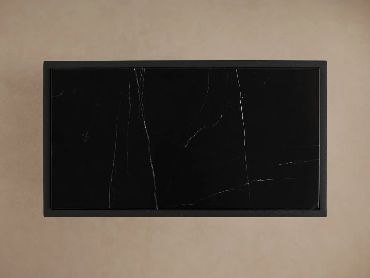 Close-up of Mills Stone C Table, showing its black hand-honed stone top with white veining on a matte black metal frame.