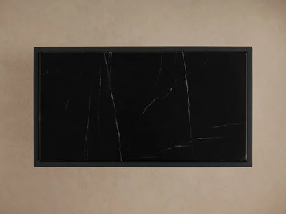 Close-up of Mills Stone C Table, showing its black hand-honed stone top with white veining on a matte black metal frame.