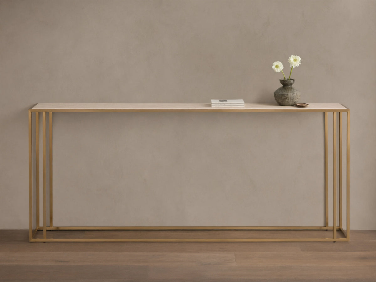 Front view of the Mills Stone Console Table with a light stone top and antique brass frame, decorated with a vase and flowers.