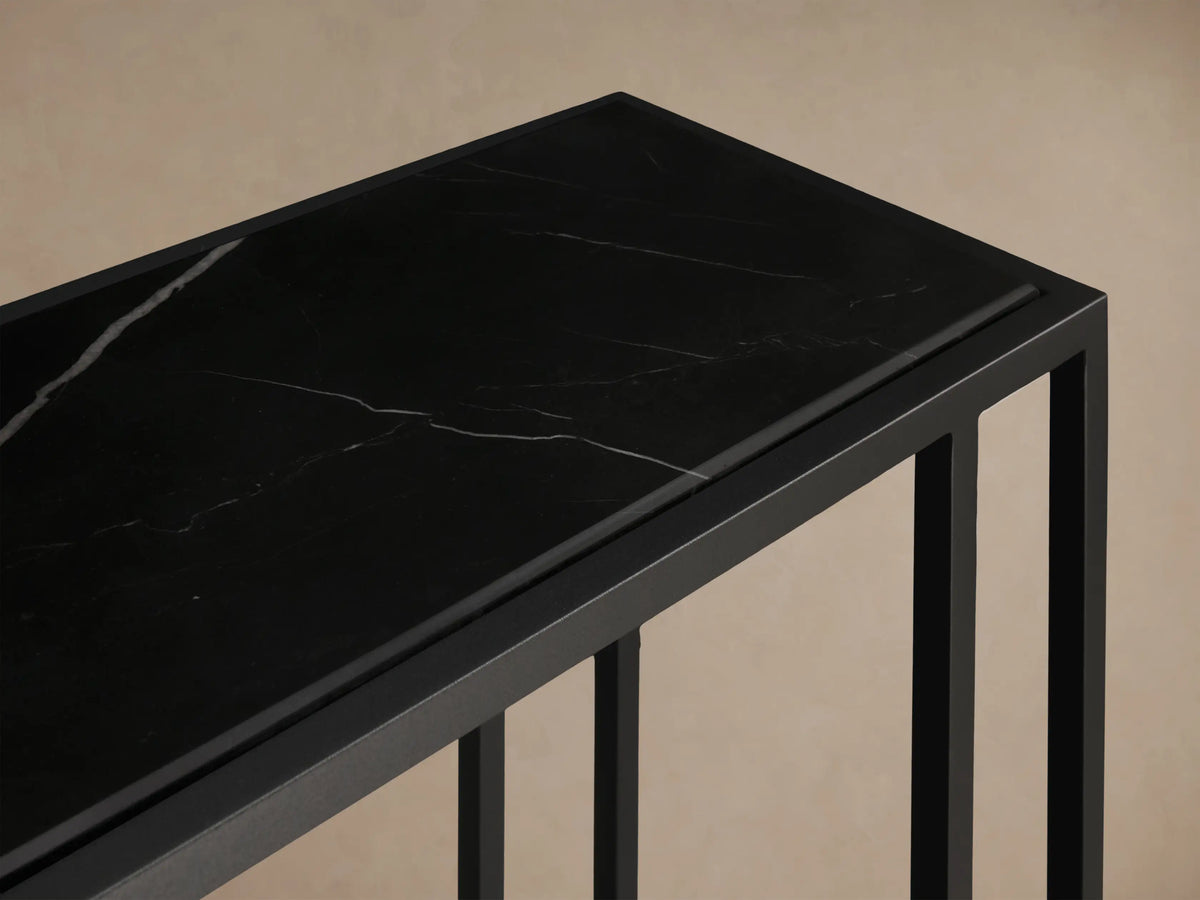 Front view of the matte black Mills Stone Console Table, featuring a dark stone top, styled with candles and a decorative object.