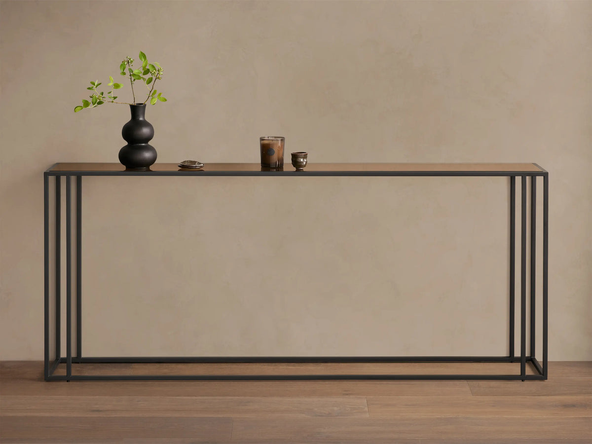 Front view of the long, rectangular Mills Glass Console Table with a clear glass top and matte black steel frame.