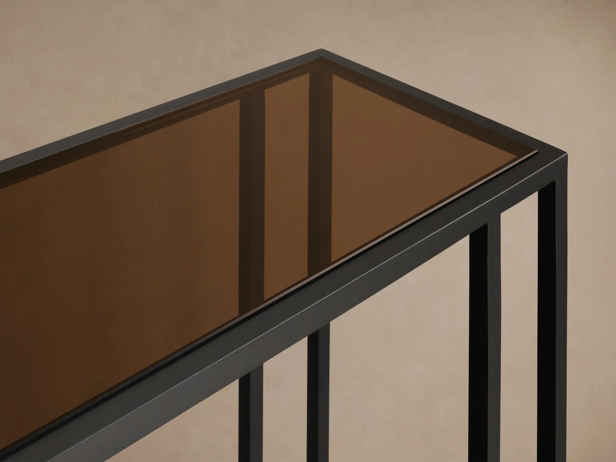 Front view of the long, rectangular Mills Glass Console Table with a clear glass top and matte black steel frame.