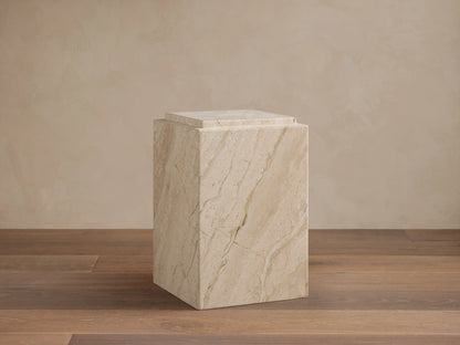 Interior view of a light stone Marmont Pedestal, cylindrical with a fluted body and round top, styled in a luxurious dining room.