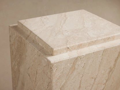 Marmont Pedestal made of natural marble with subtle veining and a matte lacquer finish. Square shape on a wooden floor.