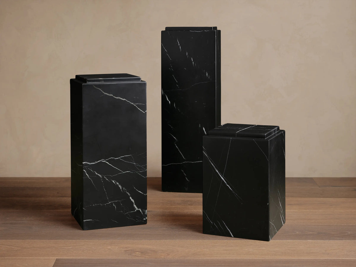 Marmont Pedestal crafted from black marble with a matte lacquer finish, showcasing unique white veining on a smooth, angular surface.