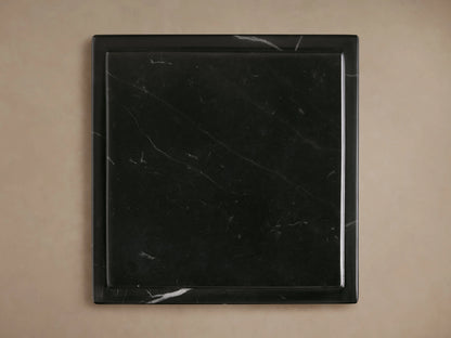 Three black marble Marmont Pedestals of varying heights, featuring striking white veining, on a wood floor.