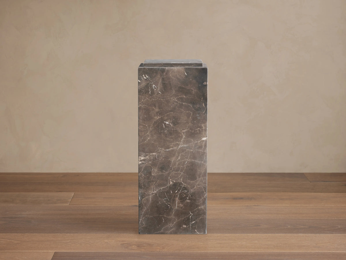 Marmont Pedestal crafted from dark marble with natural veining, rectangular shape, matte finish, on a wooden floor.