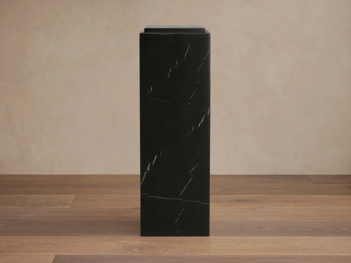 Light gray veined Marmont Pedestal, a round stone side table with a cylindrical pedestal base, visible through open doors.