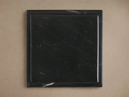 Three black marble Marmont Pedestals of varying heights on a wooden floor, featuring white veining and a matte finish.
